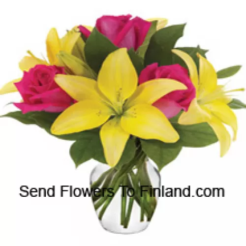 Розовые розы и желтые лилии с сезонными наполнителями красиво оформлены в стеклянной вазе